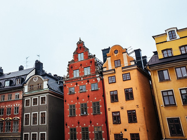 Foto från gamla stan Stockholm. Äldre hus i flera färger vid ett torg.