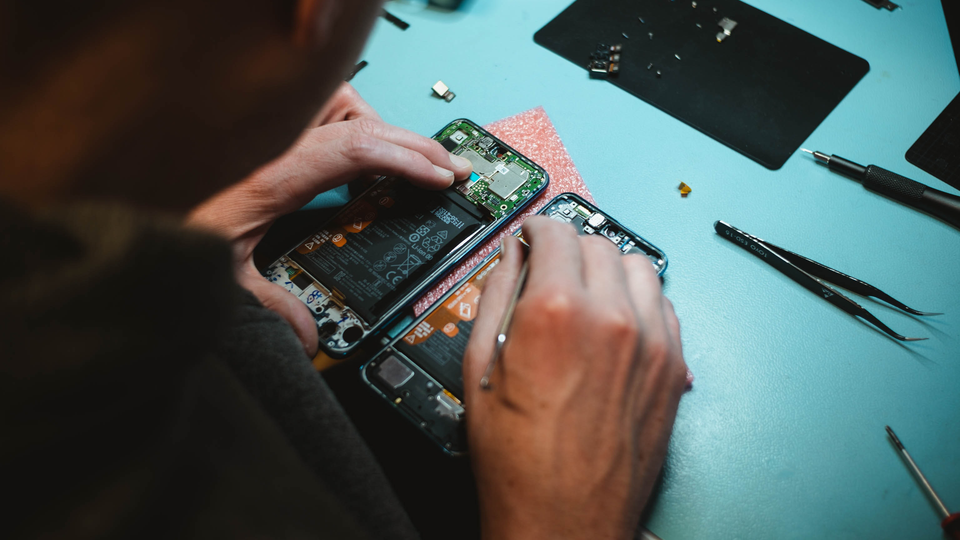 Person reparerar elektronik i en mobiltelefon