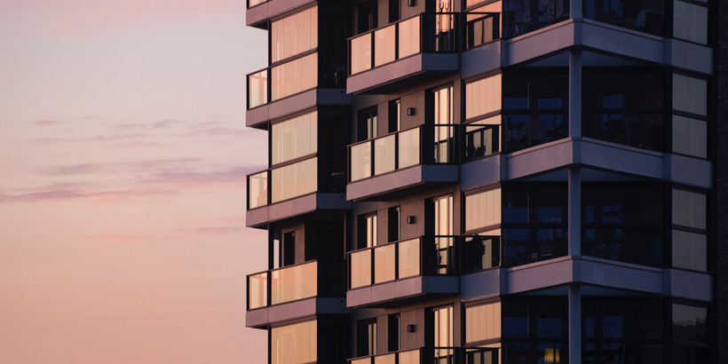 Ett lägenhetshus med balkonger i solnedgång